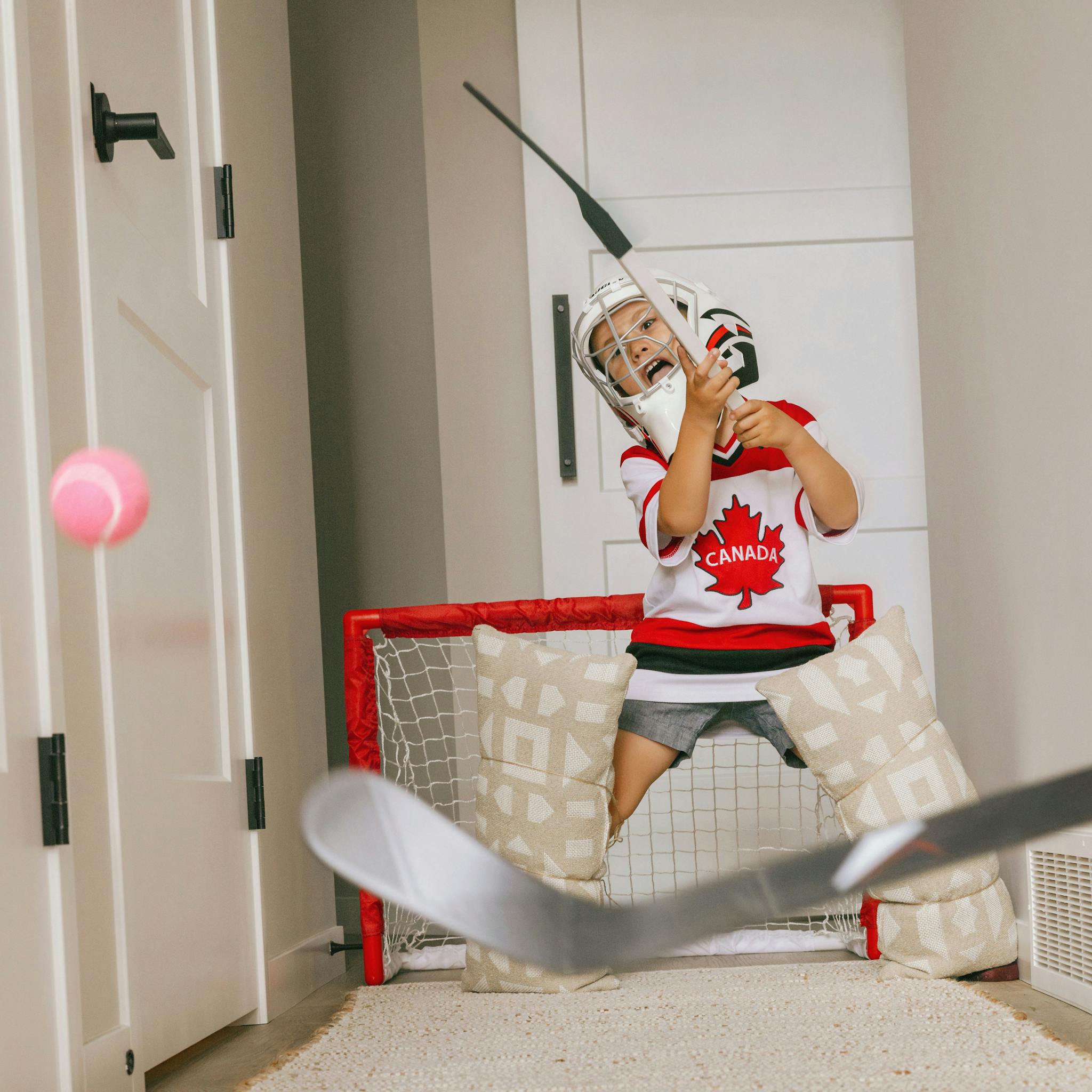 kid with hockey stick in living room